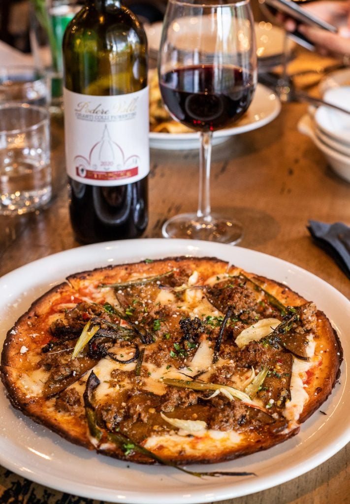 Pizza on a plate with a bottle of red wine