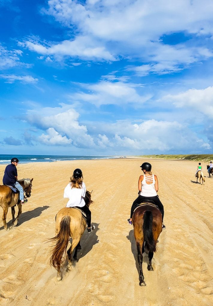 Three people horse riding on the beach in the Outer Banks