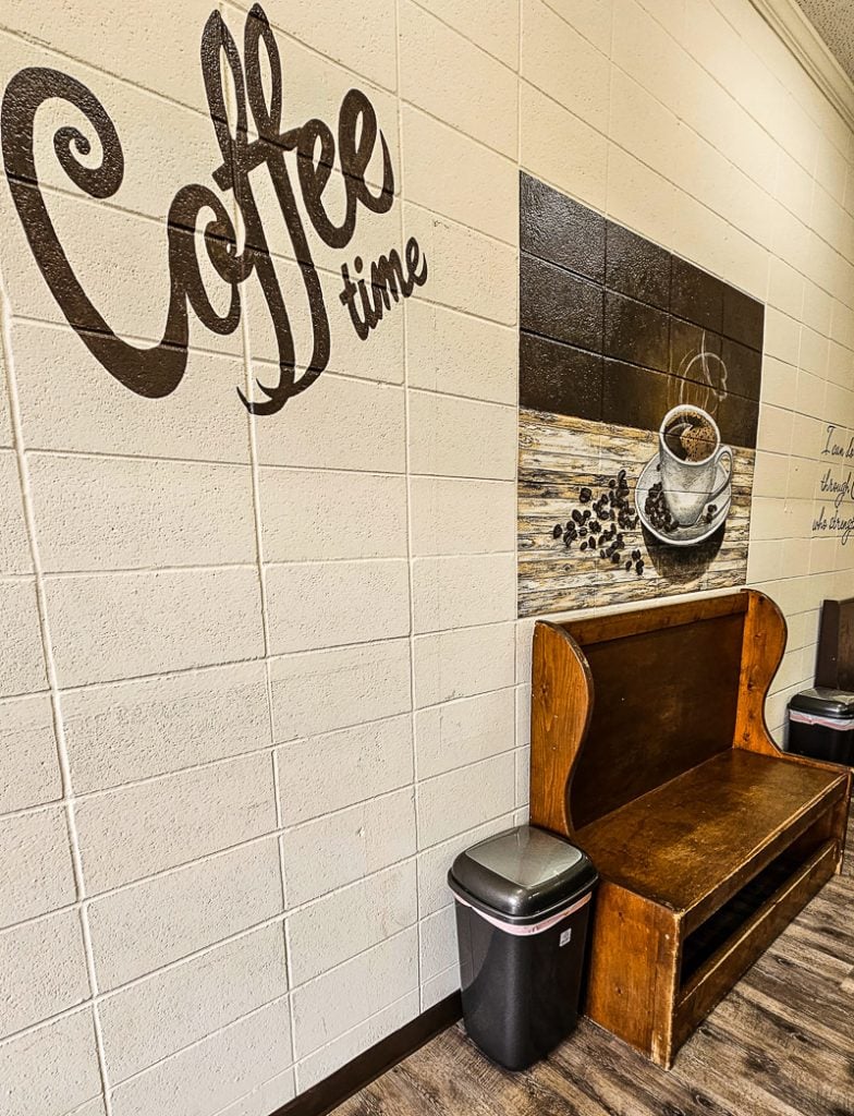 A chair and a mural on a wall saying coffee time
