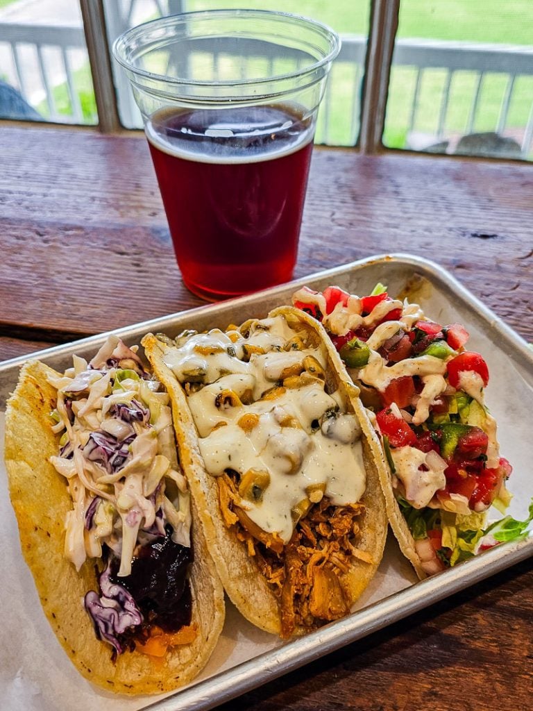Three tacos on a tray and a cup of beer