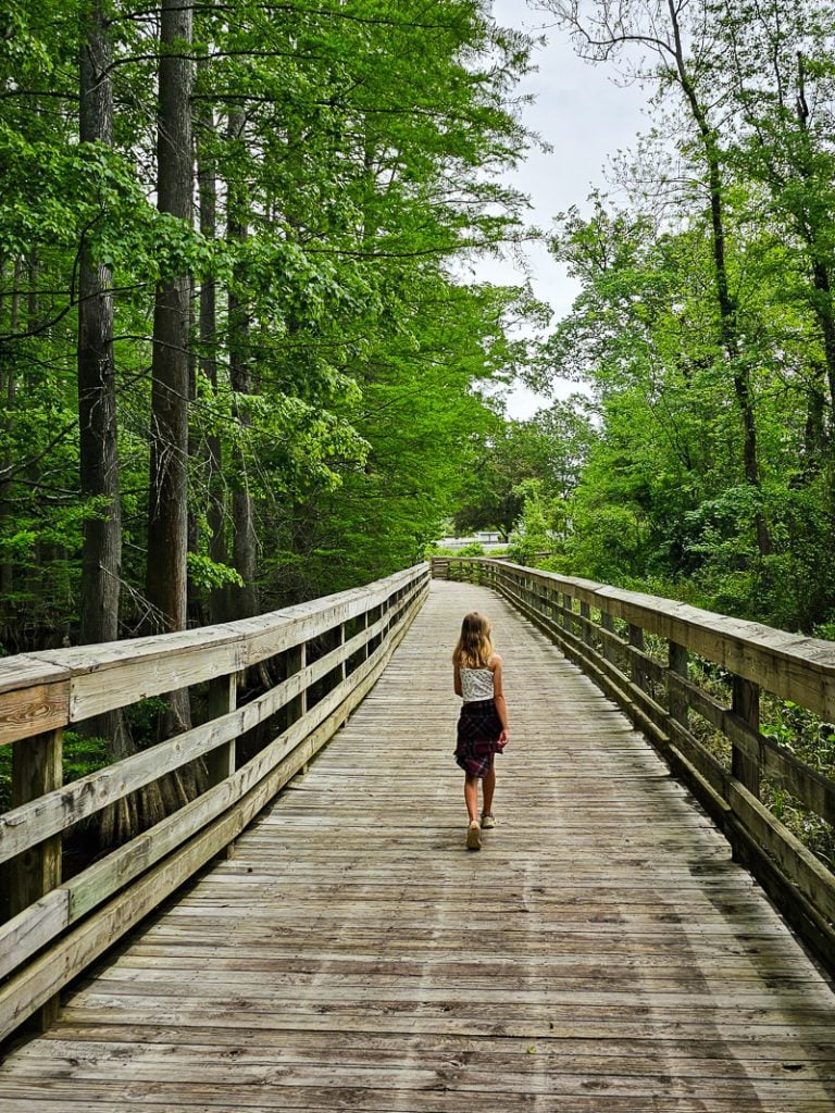 Girl walking across a boardwalk along a Greenway trail
