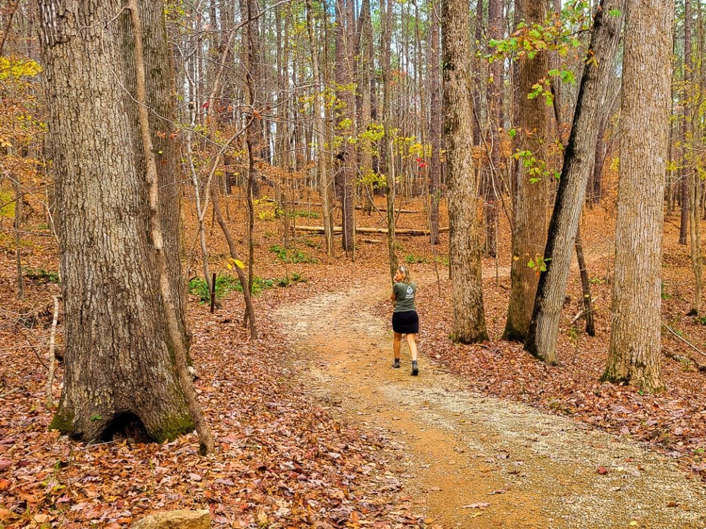 Woman walking down a hiking trail in the forest.