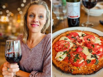 Lady drinking a glass of red wine with a pizza
