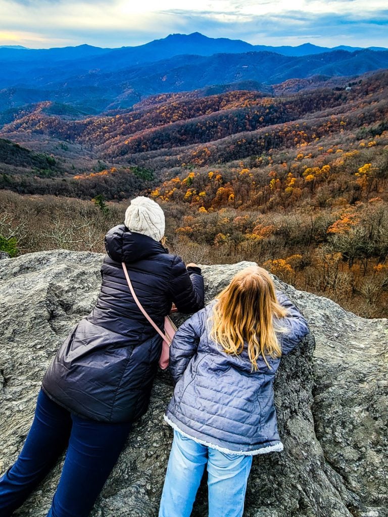 Mom and daughter laying on a rock overlooking the mountain views