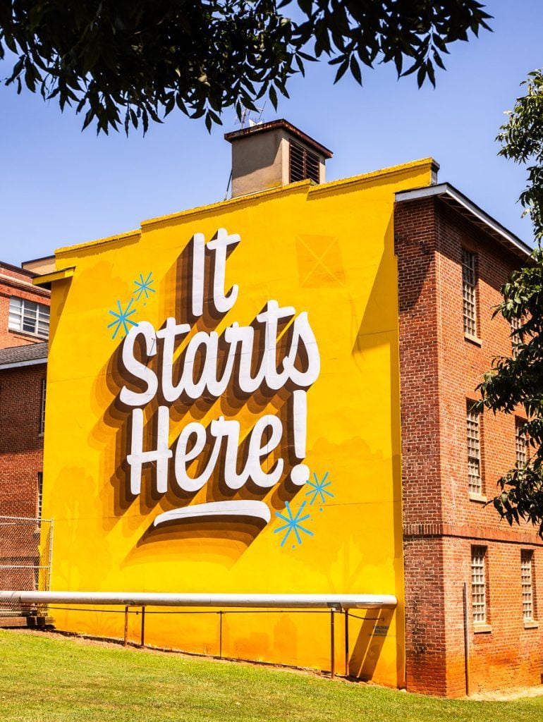 Mural on a building that says "it starts here"