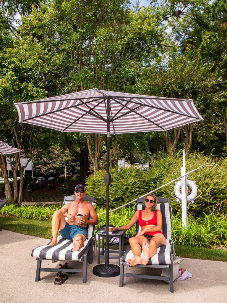 Man and woman sitting on pool chairs under an umbrella