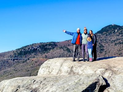 Family standing on rock ledge overlooking the mountains