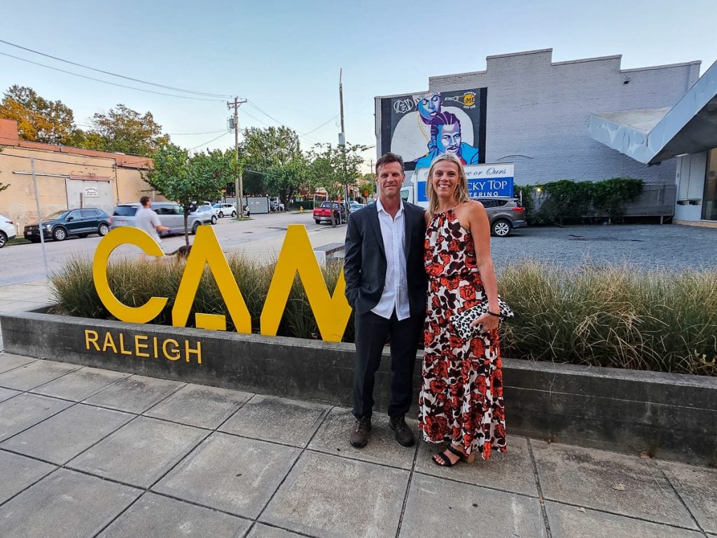 Man and woman standing in front of a sign that says CAM Raleigh