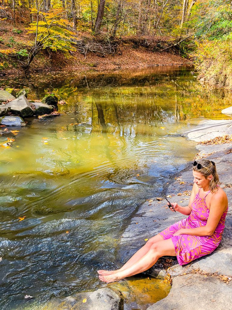 Woman sitting by a stream with feet in the water