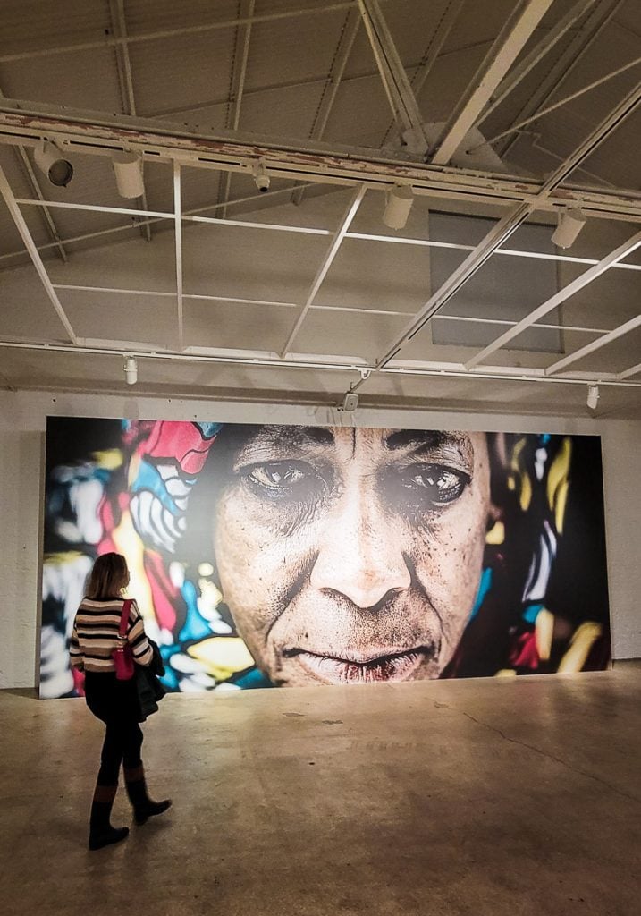 Lady in an art gallery looking at a portrait of a black woman