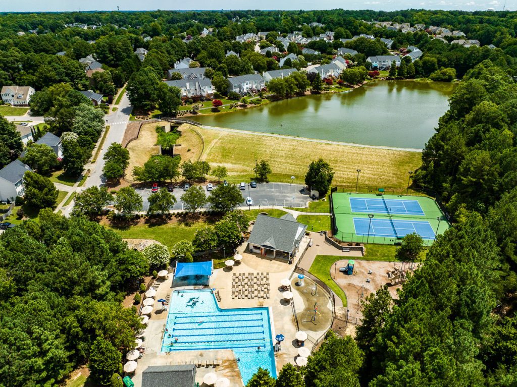 Pool and tennis courts near a lake and neighborhood homes