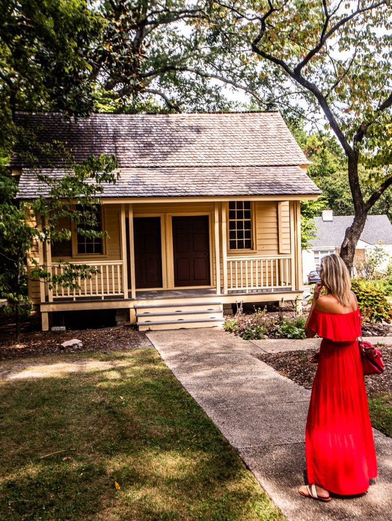 Lady in red dress walking down path toward a yellow cottage