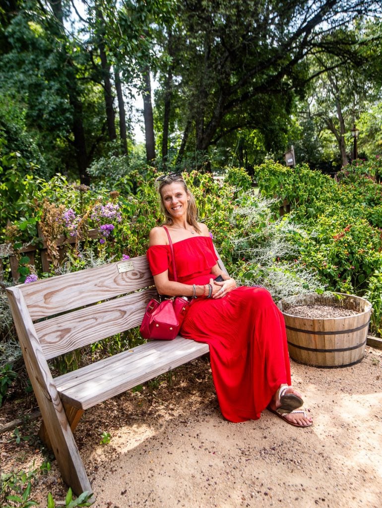 Lady in red dress sitting on a wooden bench in a garden