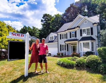 Couple standing in front of a home for sale