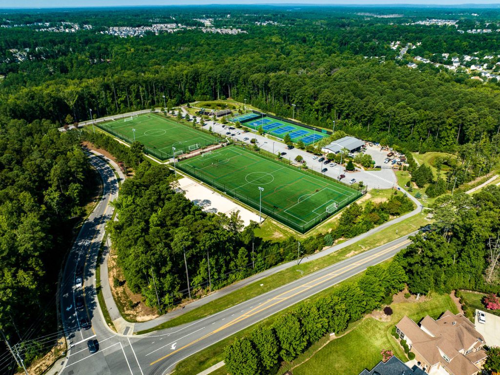 Soccer fields and tennis courts surrounded by forest