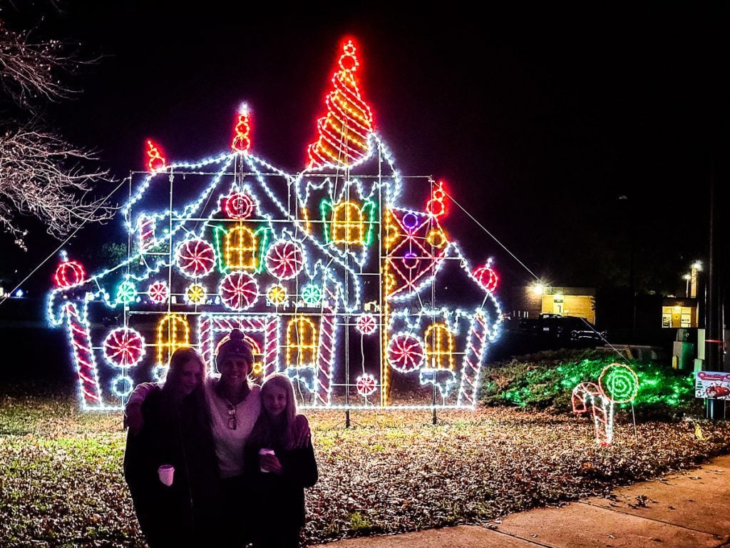 Mom and two daughters standing in front of Christmas lights