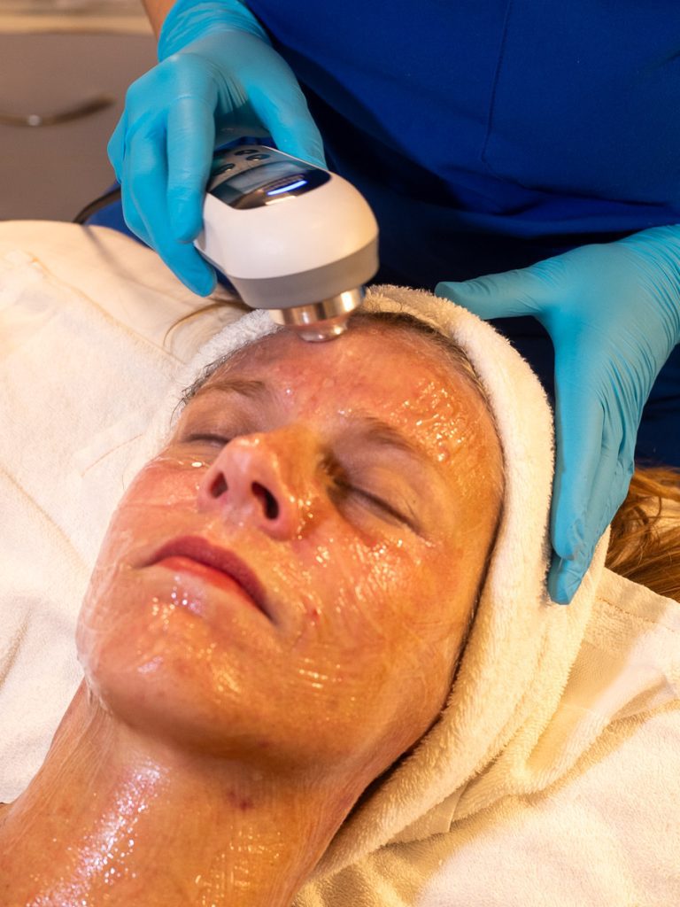 A woman lying down receiving a salt facial from a medical therapist.