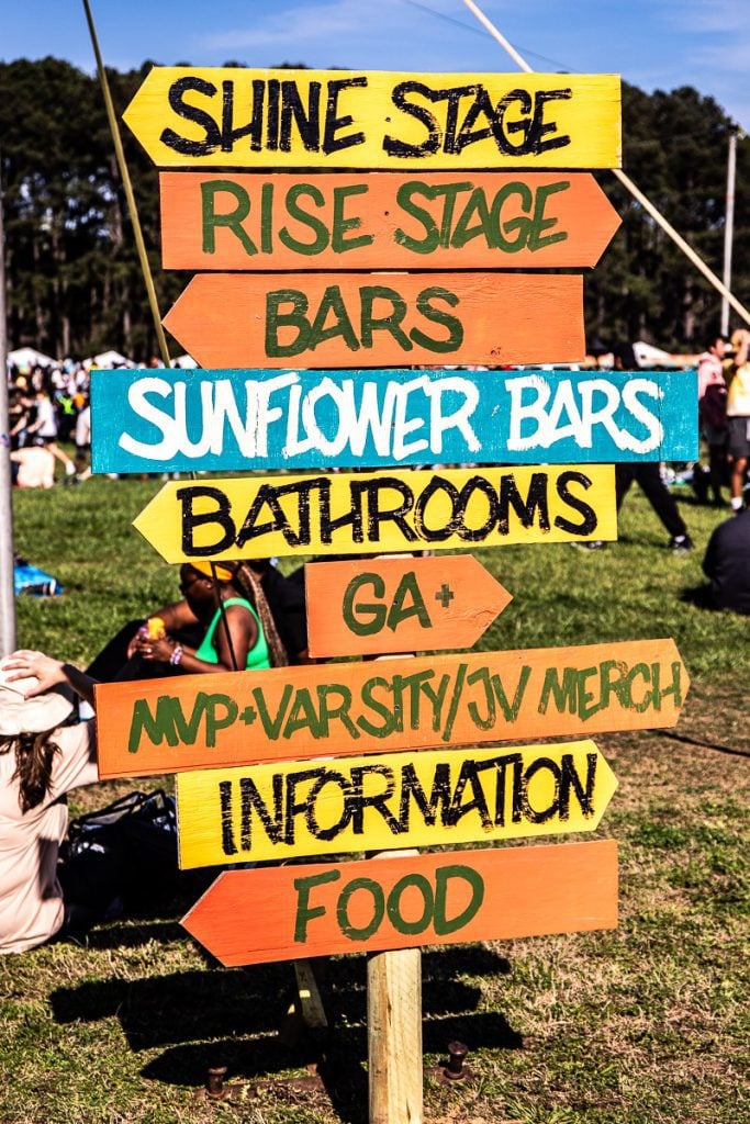 A sign at a music festival displaying directions.