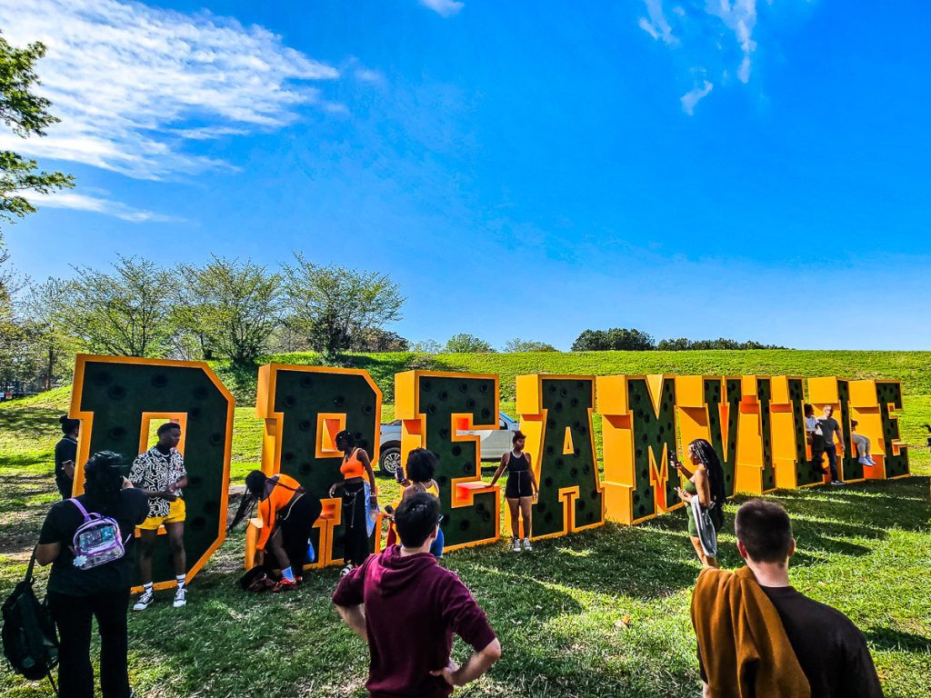 People at a music festival in front of a sign that says DREAMVILLE.