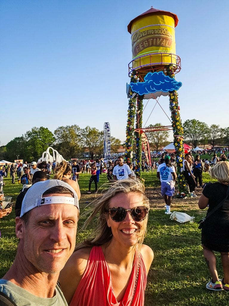 A man and a woman at a music festival in front of a water tower.