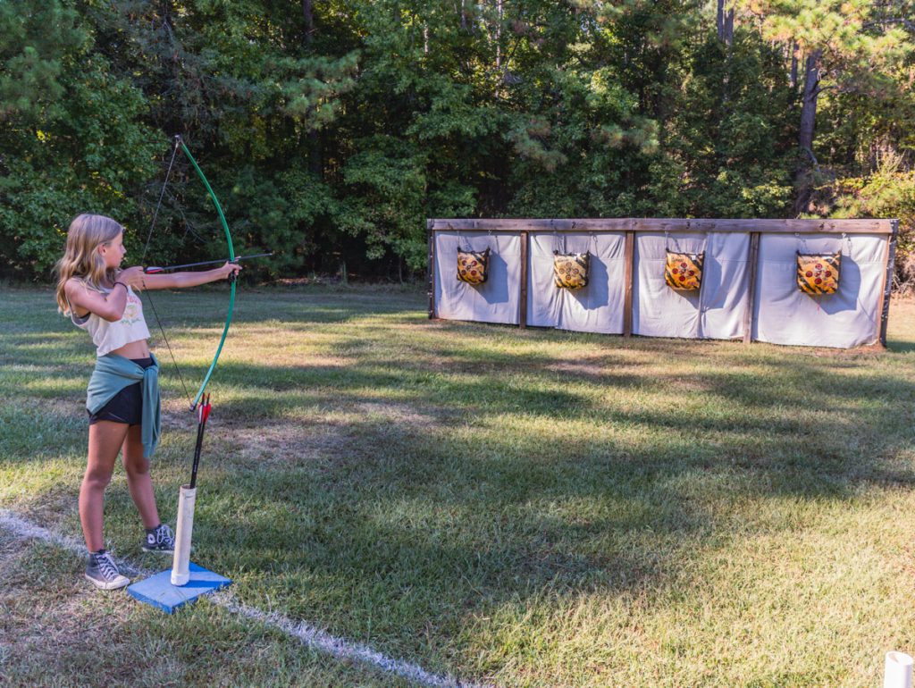 savannah pulling back on bow and arrow on archery field
