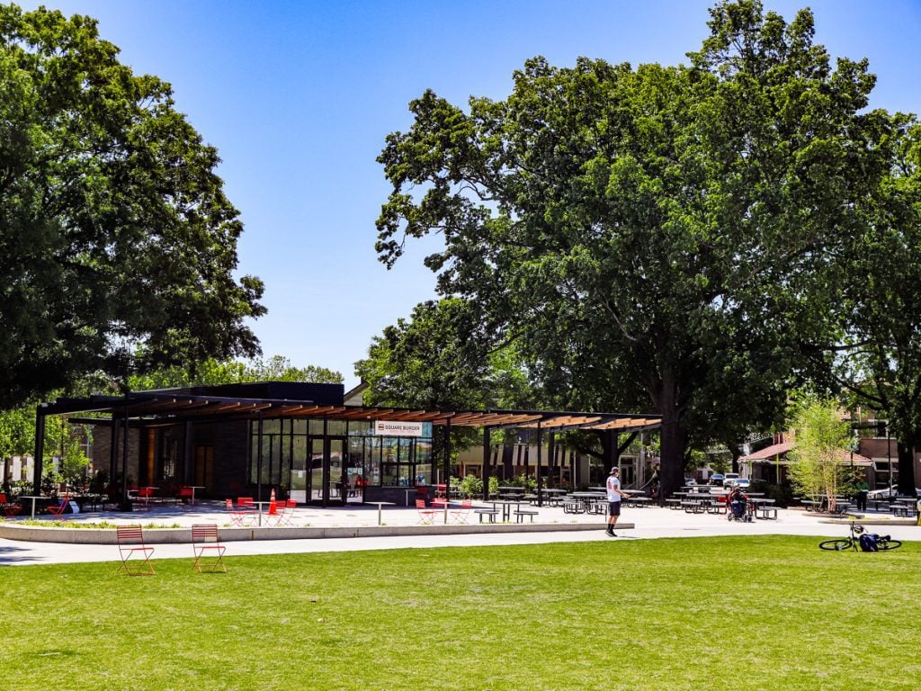 A city park with green grass, oak trees and a pavilion
