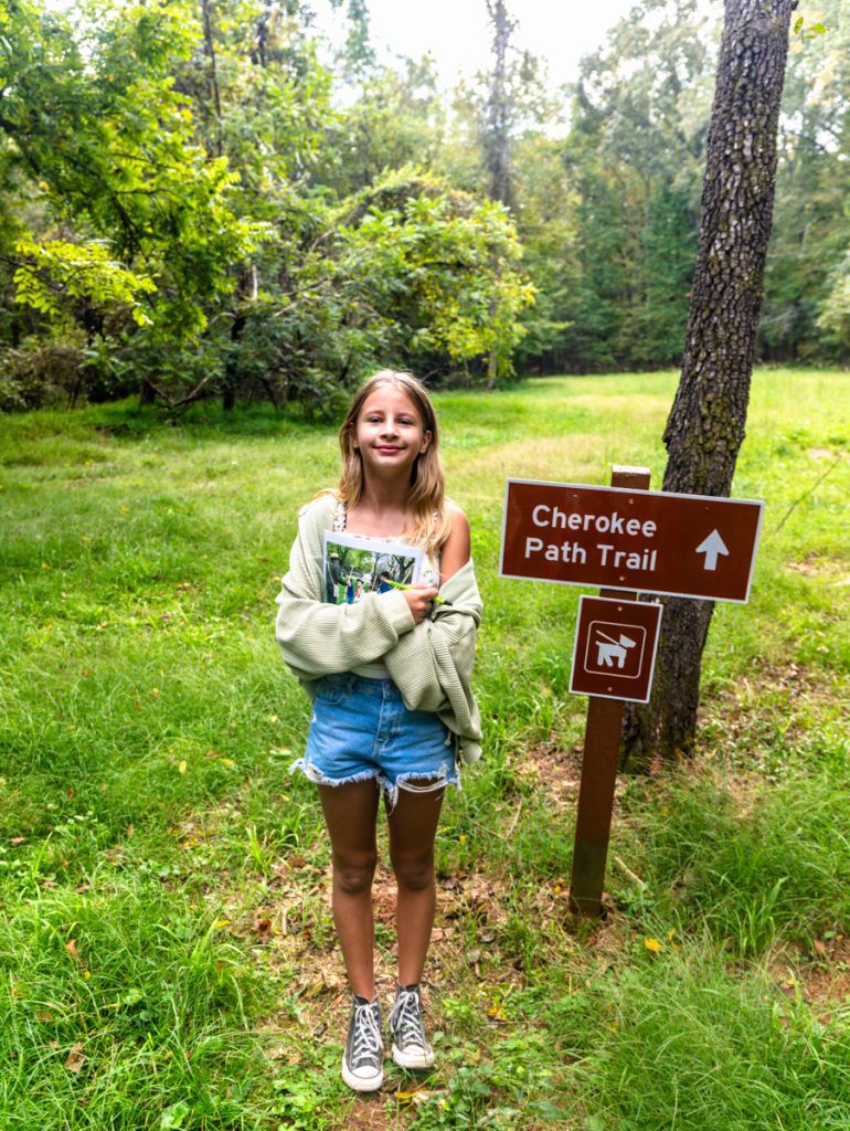 savannah standing beside cherokee trail sign