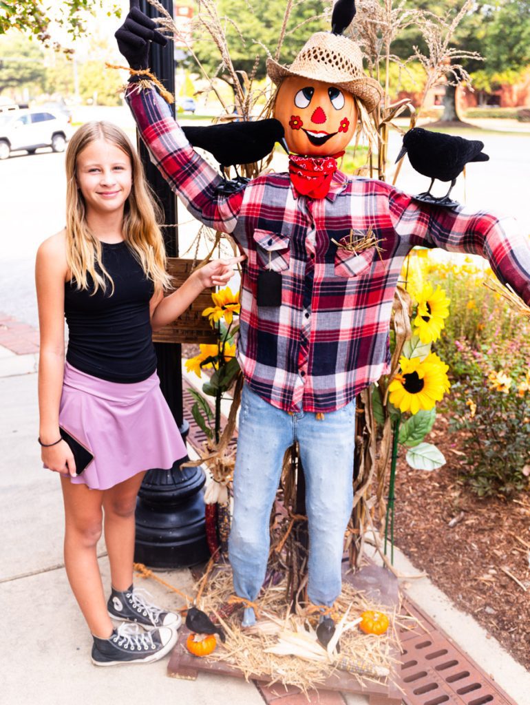 savannah standing beside scarecrow on street