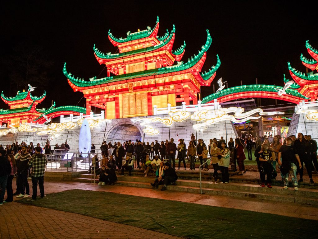 People gathered in front of a Chinese temple of lights.