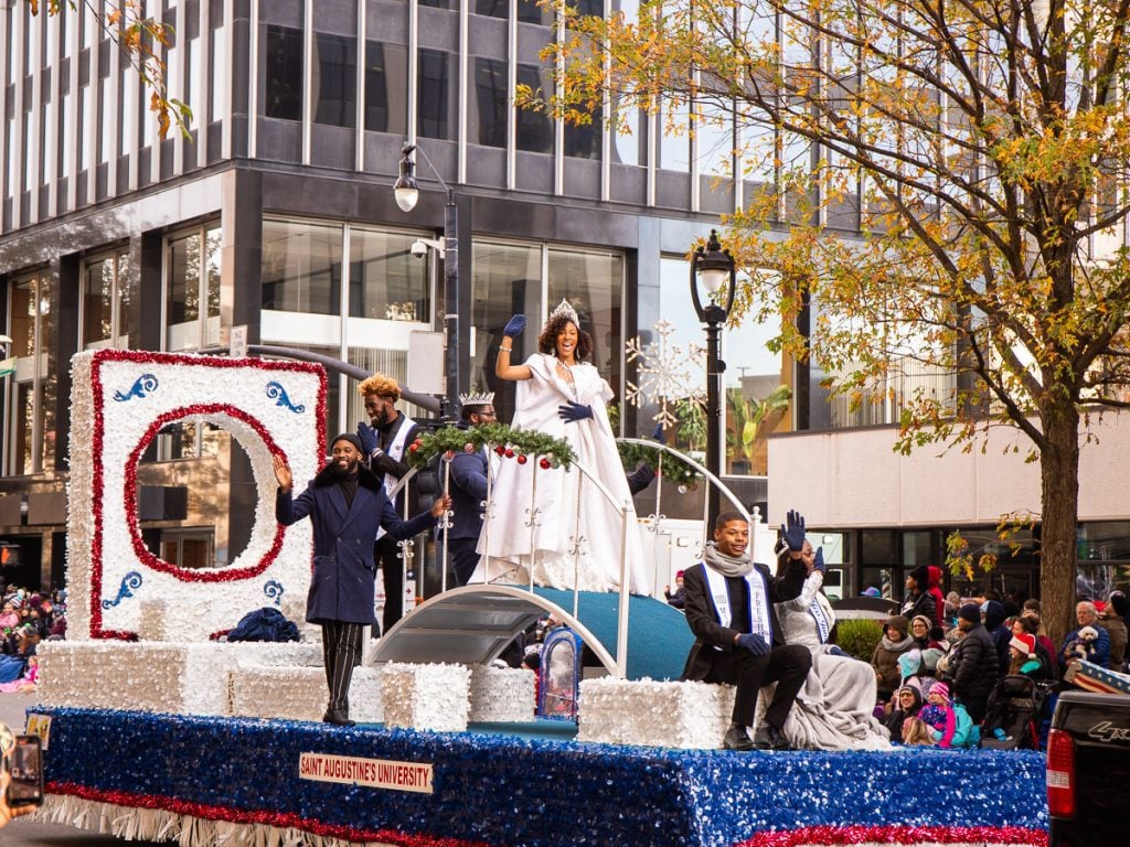 People on a float waving during a Christmas parade.
