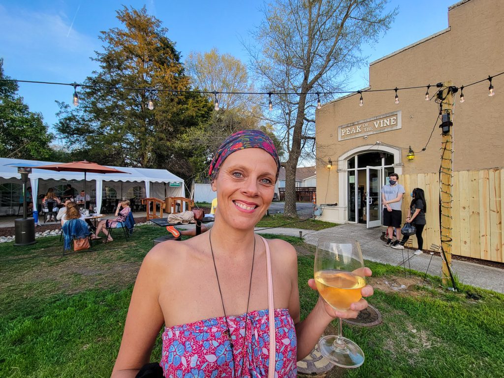 Woman standing outside holding a glass of wine.