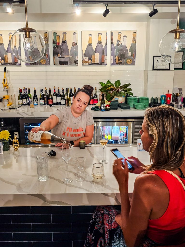 Lady pouring a glass of wine in a bar for a customer.