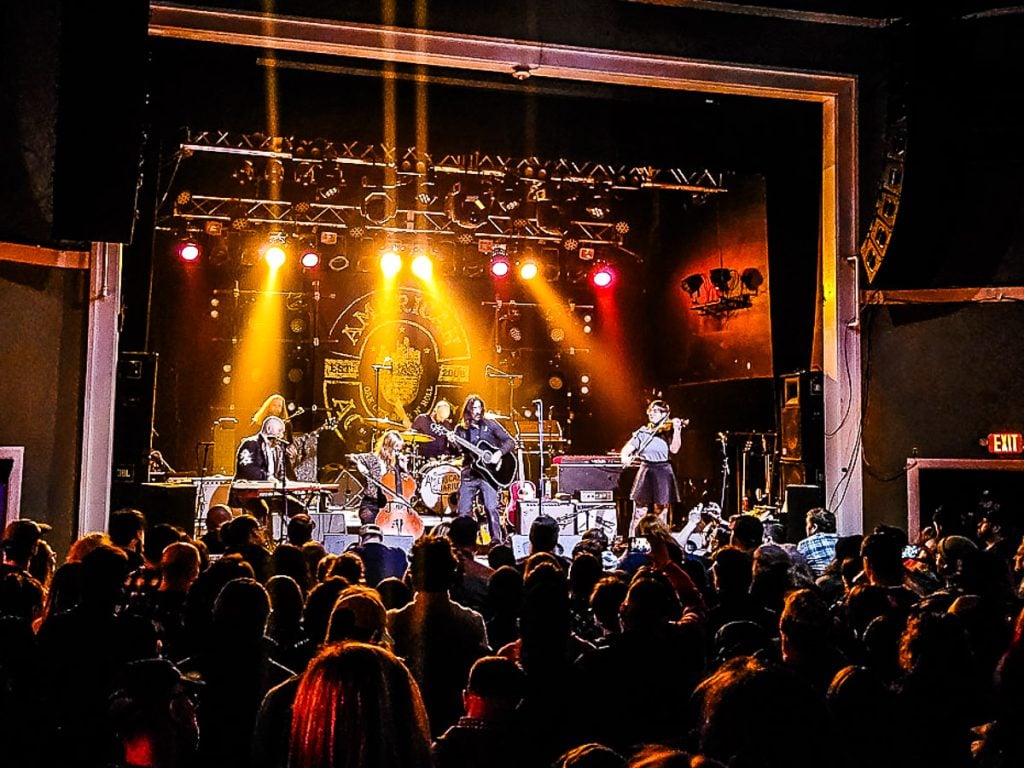 People watching a band perform on stage inside a music venue.