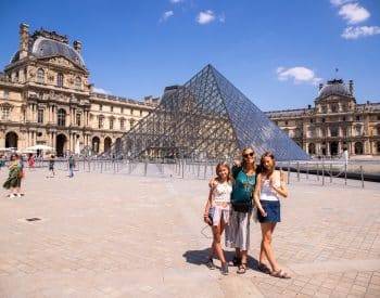 Mom and daughters in front of the Louvre Museum in Paris, France.
