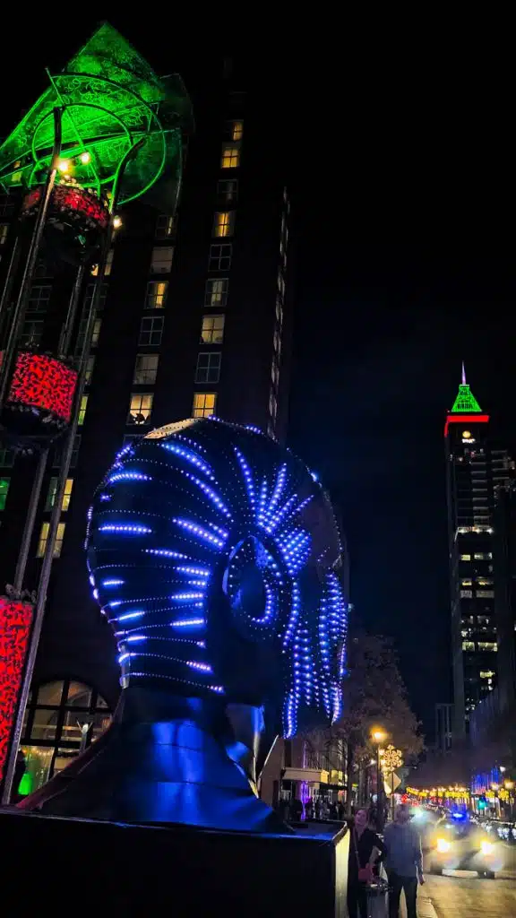 raleigh illuminated sculpture head looking at high rises
