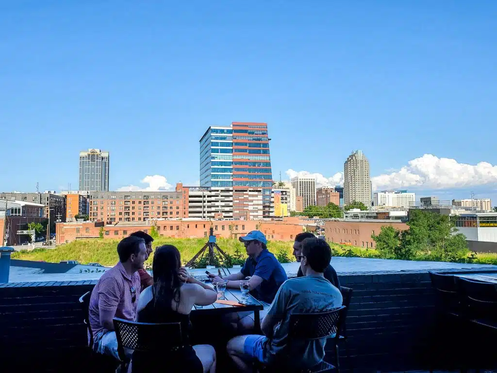 People sitting at a table drinking with a city skyline in the background.