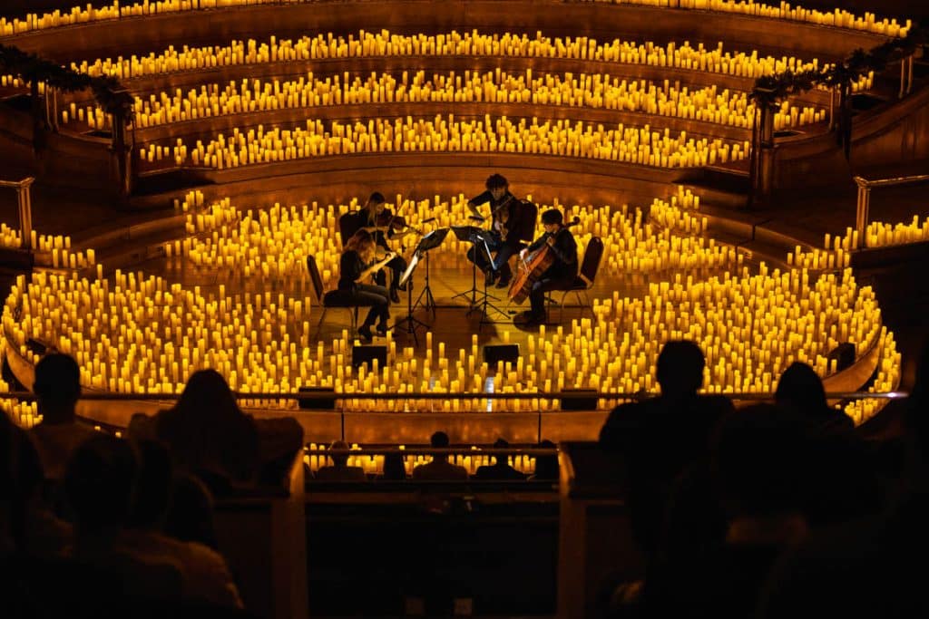 quartet playing on stage surrounded by candelight