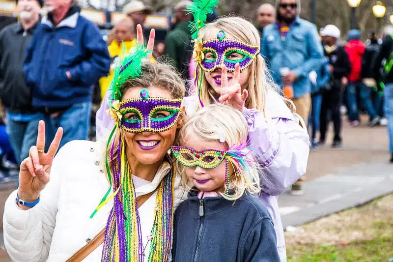 woman and children with purple mardi gras masks on