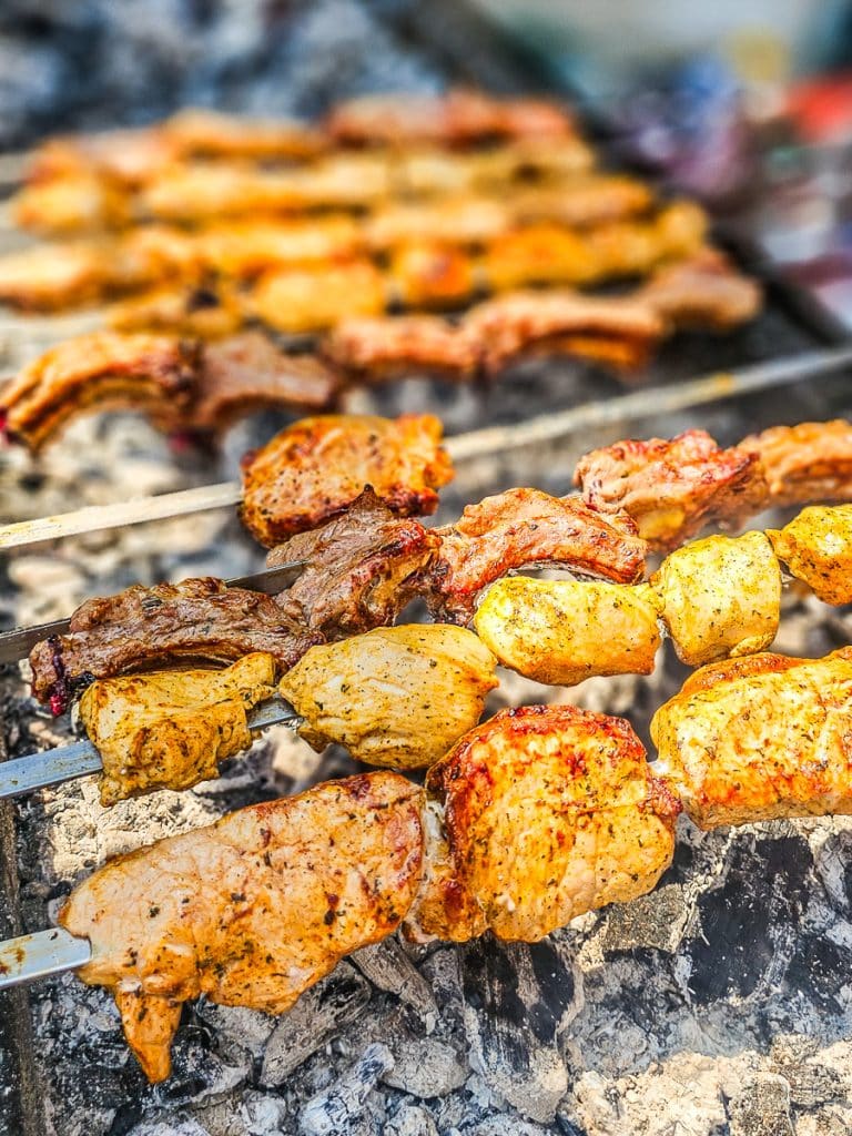 Chicken Skewers on a stick cooking over coals.