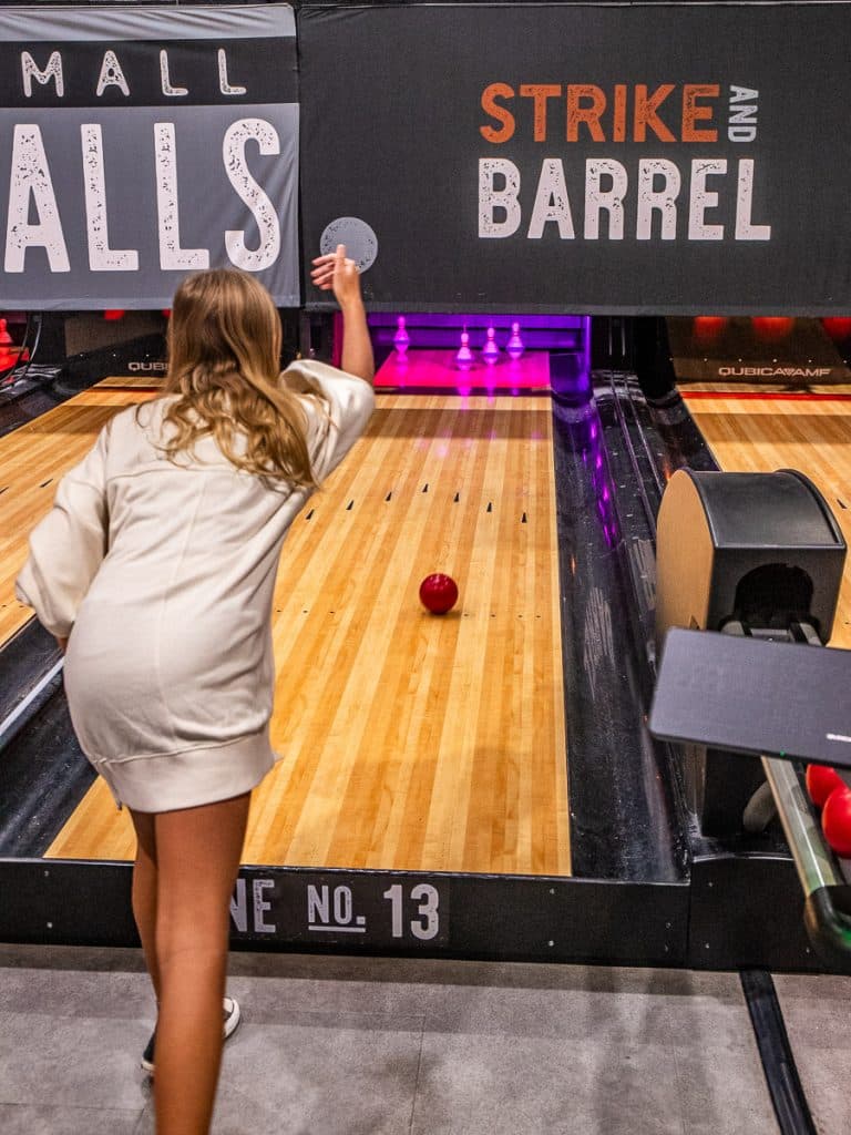Young girl doing ten pin bowling.