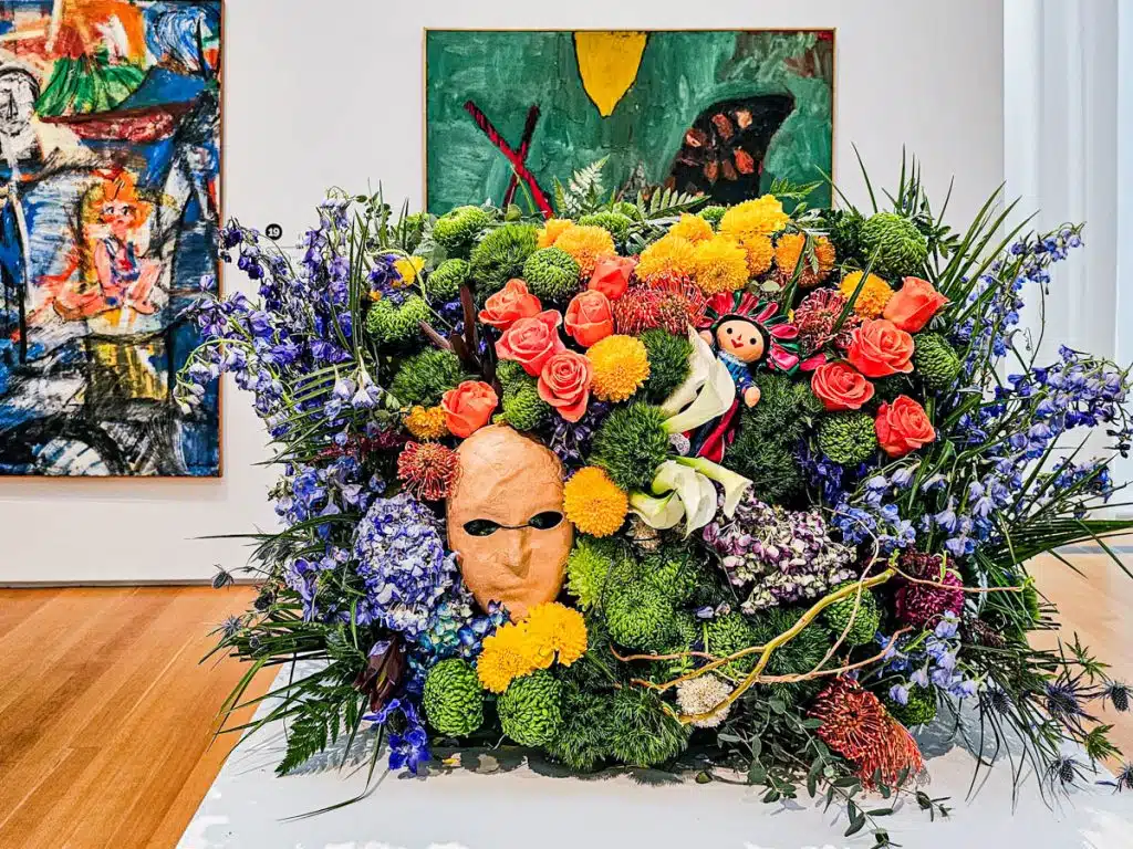 flower arrangement with mask in the middle in front of paintings in art museum