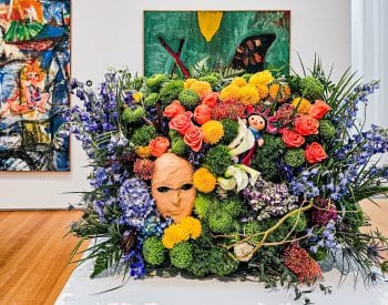 flower arrangement with mask in the middle in front of paintings in art museum