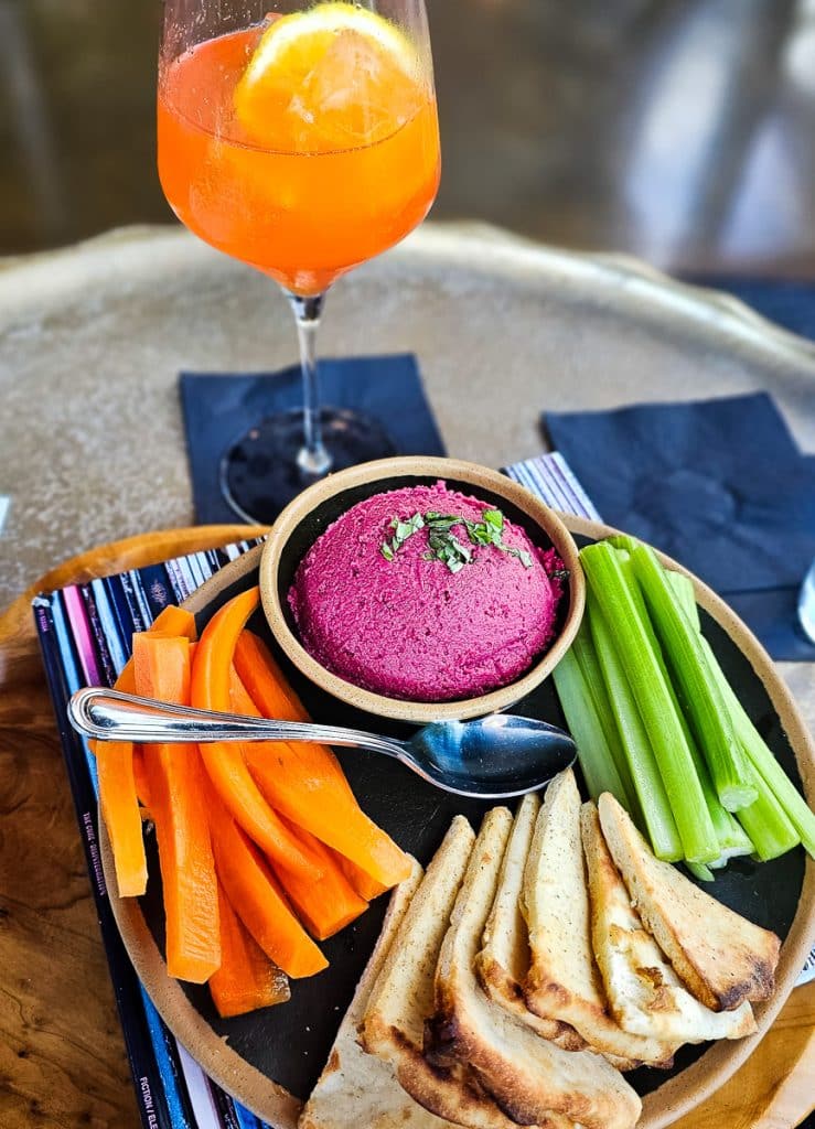 A plate of pita bread, beet hummus and a cocktail.