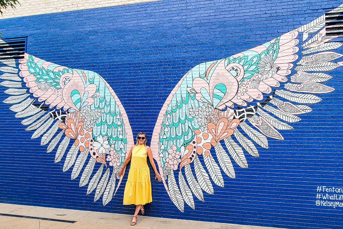 Woman standing in front of a mural of wings.