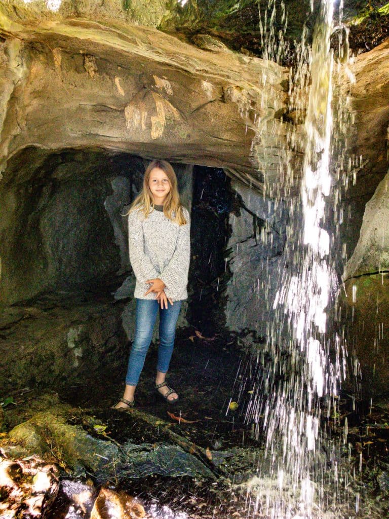 girl in cave with waterfall spilling over