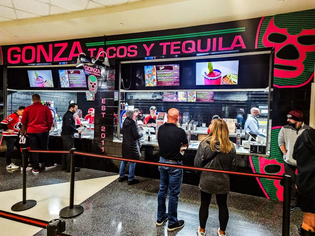 People lined up to order Mexican food inside a sports arena.