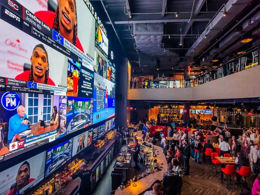 Sports bar with large TVs and people sitting at tables.