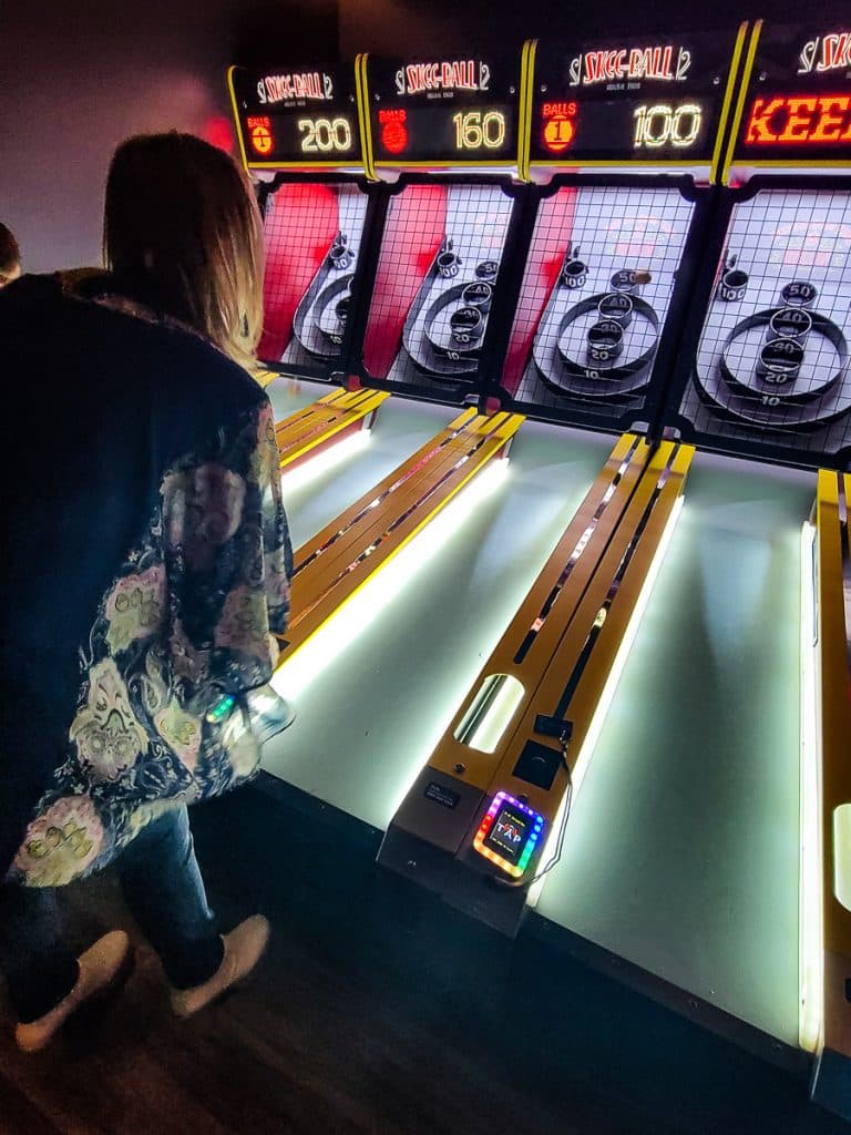 Woman playing skeg ball in a sports pub.