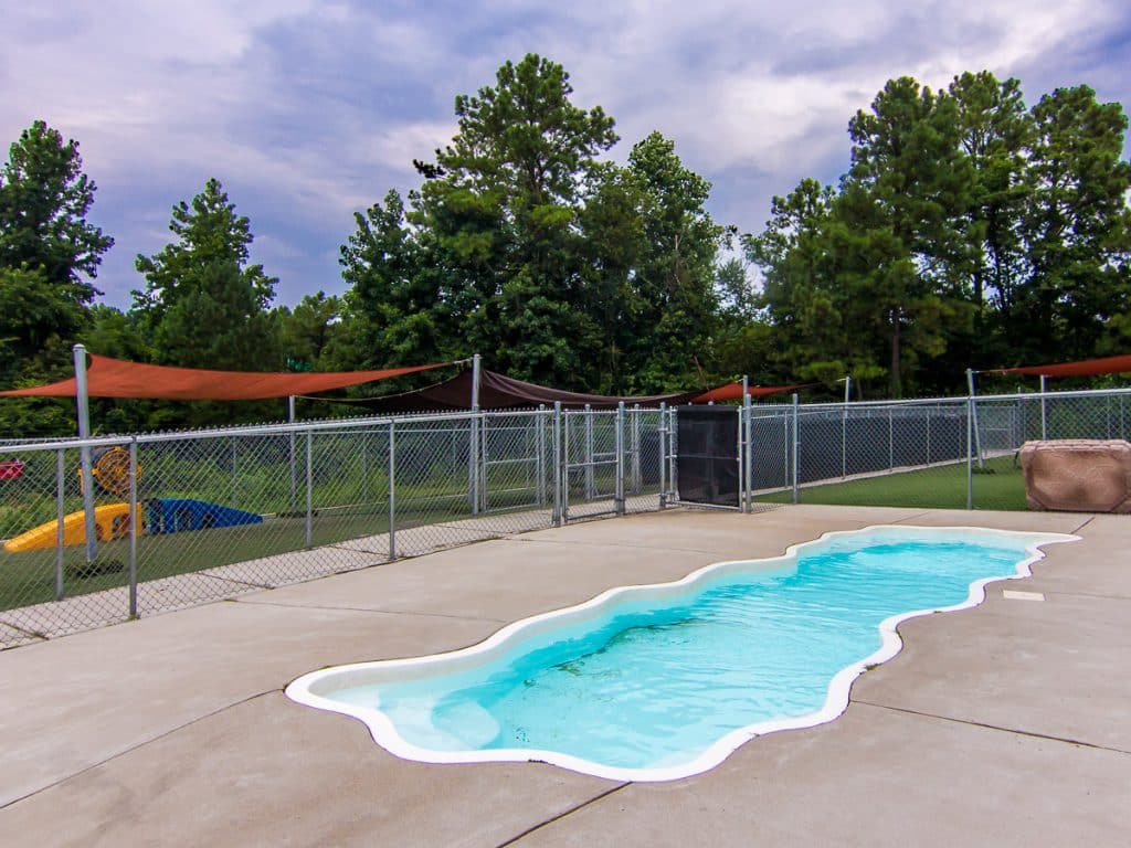 Pool surrounded by a fence at a pet resort.