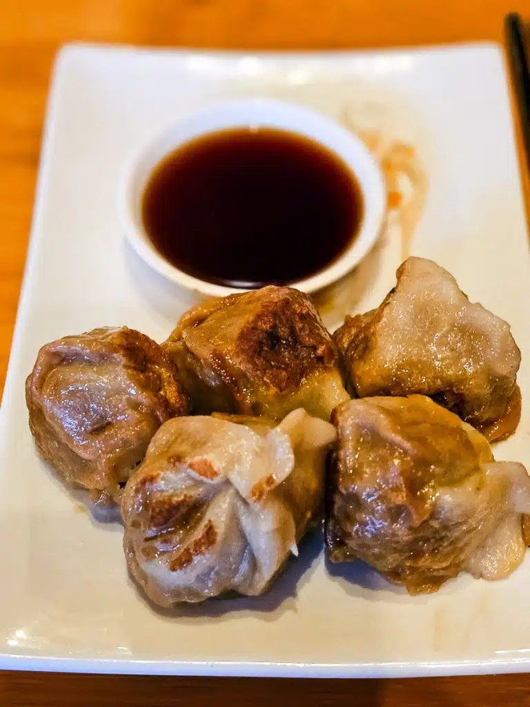 5 dumplings and soy sauce on a plate.